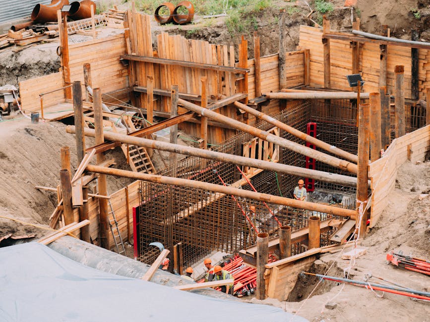 Aerial view of a construction site with workers, wooden framework, and scaffolding